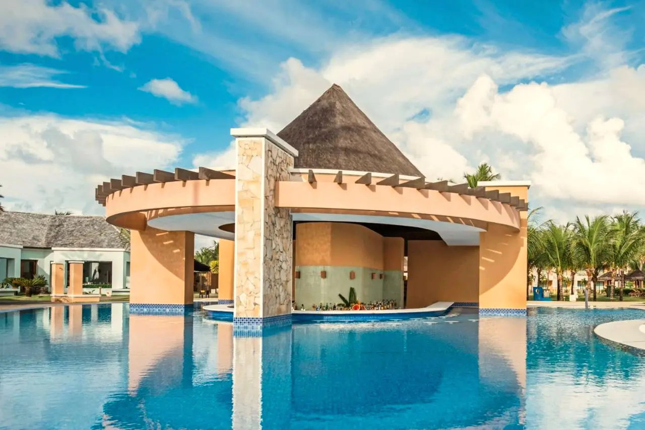 Bar com balcão dentro da piscina, sob telhado de piaçava